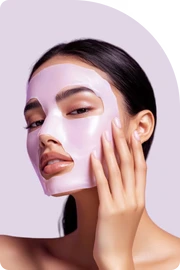 Pink facial sheet mask being applied on face for deep hydration and skin nourishment, enhancing glow and softness.