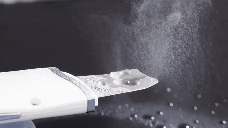 Skin scrubber with water on skin creating mist and evaporation effect, illustrating deep cleansing and hydration during treatment.